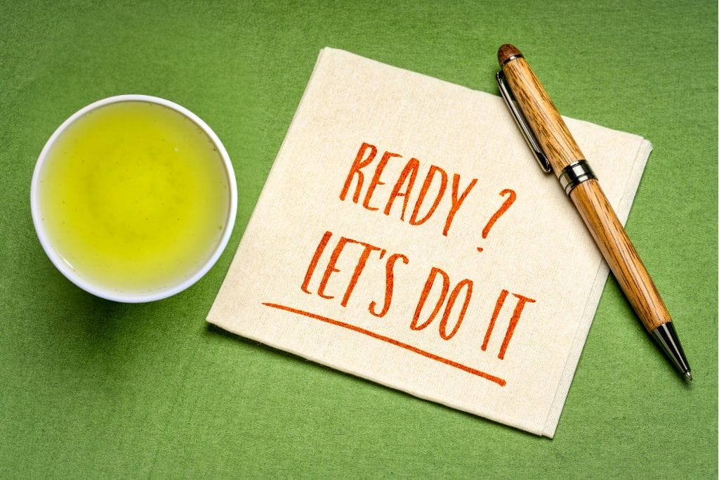 Eine Tasse mit grünem Tee, ein Stift und eine Serviette mit der Aufschrift "READY? LET'S DO IT" in roter Schrift auf einer grünen Fläche. grüner tee zum abnehmen.