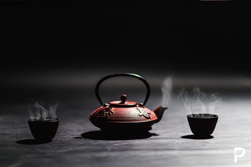 Traditionelle japanische Teezeremonie mit dampfendem grünem Tee in eleganter Eisenkanne

